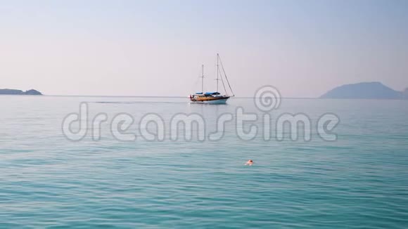 在夏日的大海里一个放松的美丽女孩躺在背上背景是船视频的预览图