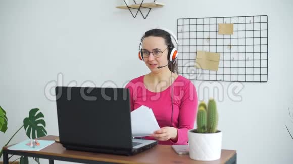 带耳机的年轻女性在家工作视频的预览图