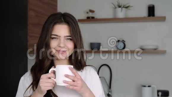 检疫期间厨房里的年轻女子一个人站着喝白杯子里的咖啡或茶很漂亮的女孩视频的预览图