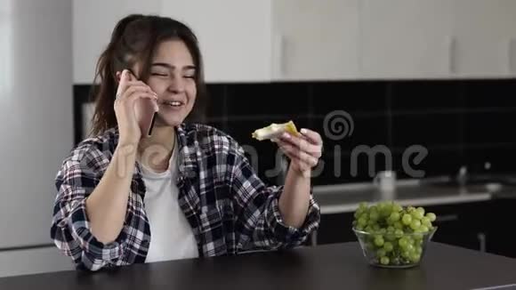 检疫期间厨房里的年轻女子喜欢吃三明治和奶酪和电话交谈情绪视频的预览图
