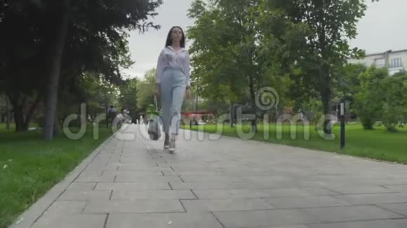 年轻女子拿着带蔬菜的棉网购物袋在夏季公园散步零浪费购物视频的预览图