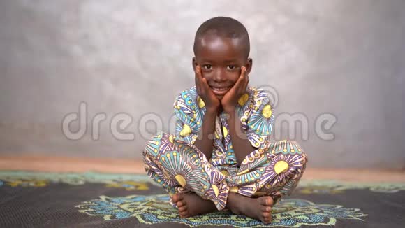 微笑的小非洲男孩坐在垫子上头靠在手上视频的预览图