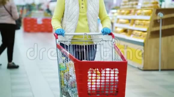 大流行病期间超市里戴着手推车购物手套的妇女视频的预览图