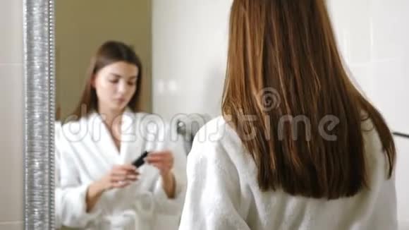 清晨年轻女子穿着浴袍在酒店镜子里看着自己天生甜美的女性视频的预览图