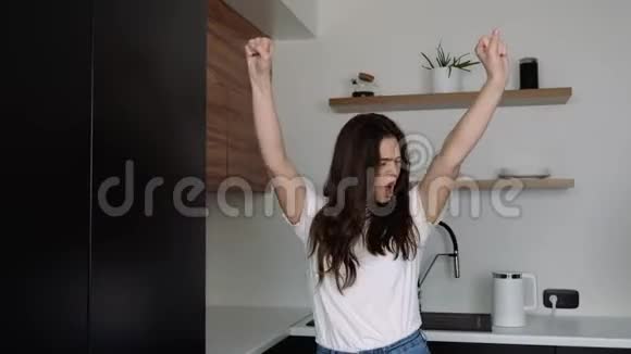 检疫期间厨房里的年轻女子因为幸福而享受和尖叫手舞足蹈视频的预览图