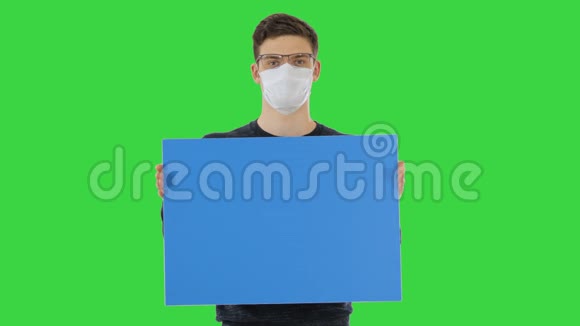 戴着医疗面具的年轻人在绿色屏幕上显示和显示标语牌Chroma键视频的预览图