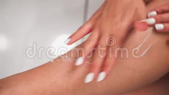 一个漂亮的年轻女孩把奶油涂在皮肤上女人的脚用润肤霜身体护理关门视频的预览图