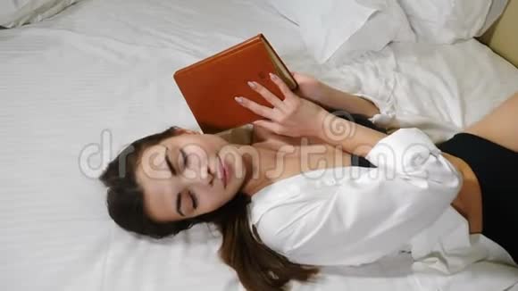 美丽的年轻女士躺在大床上手里拿着一张写字纸在家里放松旅馆里漂亮的女人视频的预览图
