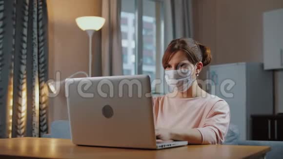 戴着医用口罩的女人远离家庭工作视频的预览图