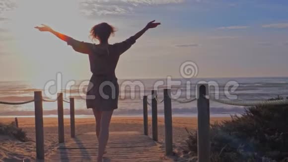 在海滩的木制走道上穿裙子的美女视频的预览图