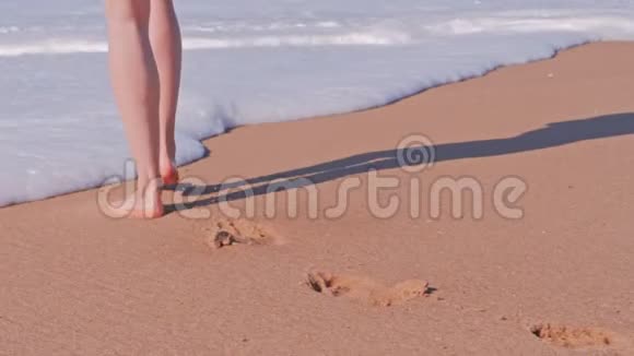 美丽的泡沫海浪在沙滩上散步的女人视频的预览图