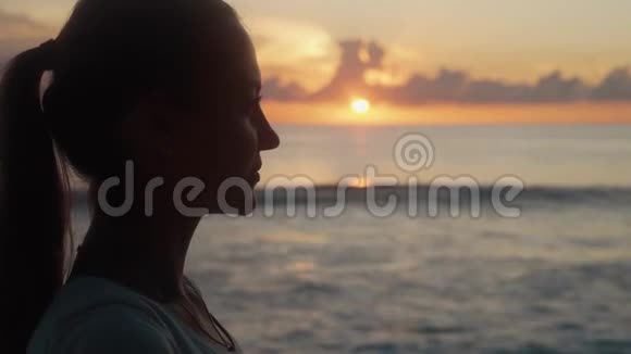 在海边日落时女人从瓶子里喝清水视频的预览图
