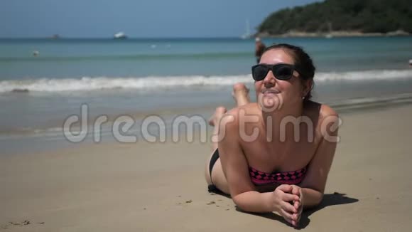 女孩躺在沙滩上享受海浪冲浪的假期视频的预览图