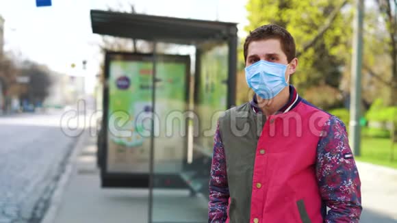 戴着医疗面具的年轻人在空车站等公共汽车视频的预览图