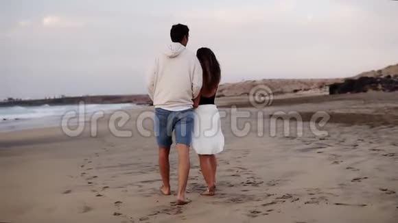 轻松的年轻夫妇在海滩上散步恋爱中的男人从背后抱着他的女孩男女旅行放松视频的预览图