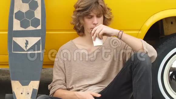 坐在城市公园喝咖啡放松的年轻人视频的预览图
