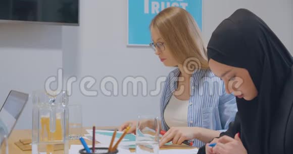 办公室里有四种不同的工作色彩鲜艳的纸张商业女孩的图形女人的头巾集中在办公室里视频的预览图