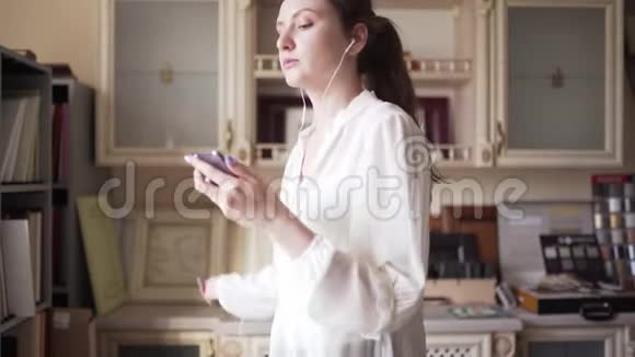 一个带耳机的女卖家在商店里工作时听音乐和跳舞女经理跟着一首歌唱歌视频的预览图