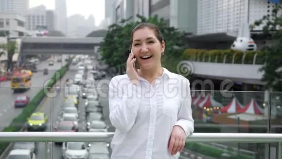 年轻女子在白色智能手机上讲话笑得开心视频的预览图