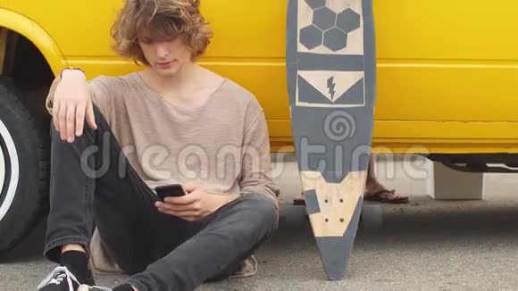 年轻的嬉皮士在旅途中坐在他的黄车旁边视频的预览图