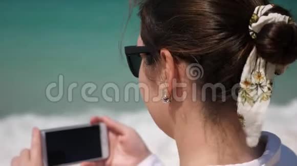 年轻的黑发女人在海滩上拍视频视频的预览图