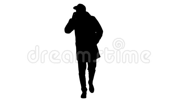 剪影休闲男子穿着户外服装和医用口罩走路和打电话视频的预览图