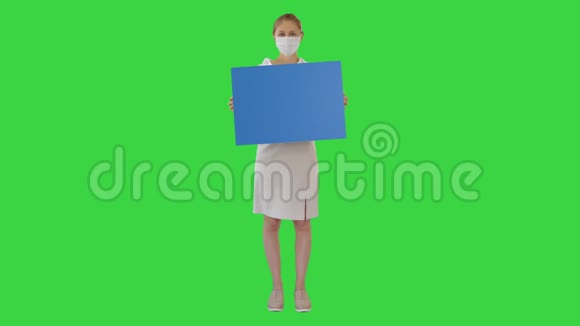 女商人戴着医疗面具在绿色屏幕上举着空白板铬钥匙视频的预览图