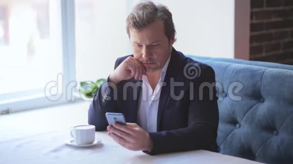 一个穿商务服的商人坐在咖啡馆里打电话视频的预览图