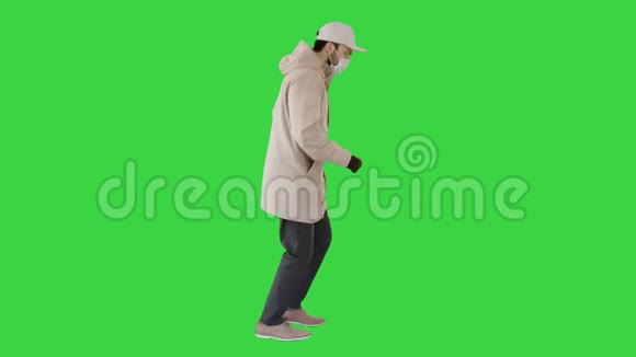 年轻人穿着户外衣服和医用口罩在绿色屏幕上慢跑Chroma键视频的预览图