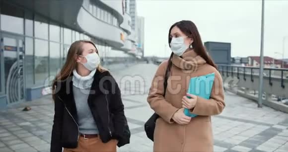 流行病期间的社会保健两个戴着口罩的白种人年轻医生女在空城街上散步视频的预览图