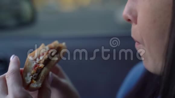 女孩在车里吃芝士汉堡慢动作视频的预览图