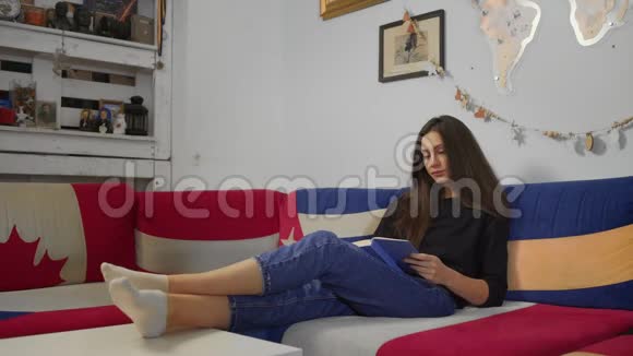 年轻女子坐在舒适的沙发上看书视频的预览图