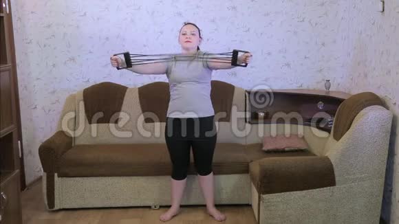 在客厅里锻炼身体的年轻女子用扩张器做伸展运动视频的预览图