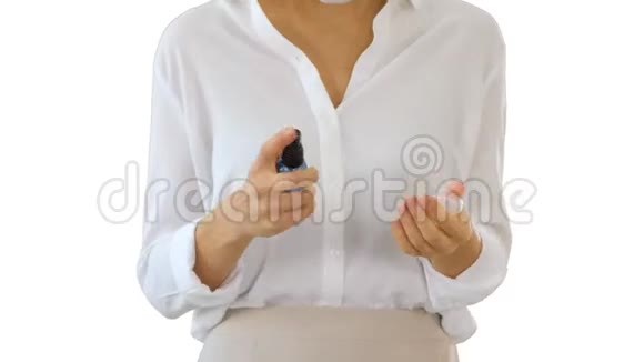 年轻女性在白色背景下行走时使用皮肤消毒器保护她的手免受任何病毒的影响视频的预览图