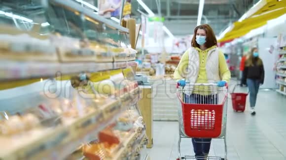 戴着医用面具的年轻女子选择超市里的新鲜面包店视频的预览图