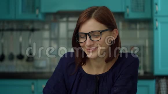 30多岁的年轻女人在蓝色厨房的家里吃披萨戴眼镜的女伴在享受披萨看着镜头视频的预览图