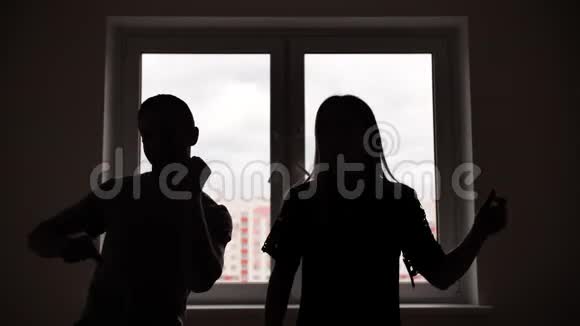 新婚夫妇的剪影在他们公寓里的窗户背景上跳舞视频的预览图