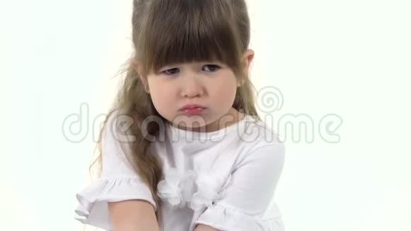 可爱的小女孩鼓起脸颊坐在白色的背景上孩子的情感慢动作关门视频的预览图