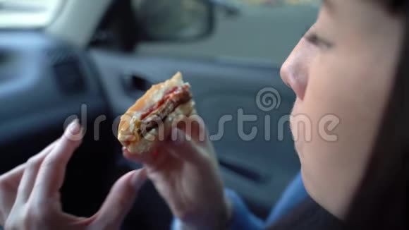 女孩在车里吃芝士汉堡慢动作视频的预览图