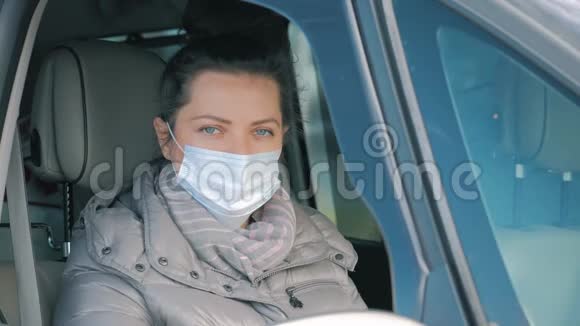 女在车上脸上戴着外科口罩打开车窗COVID19冠状病毒视频的预览图