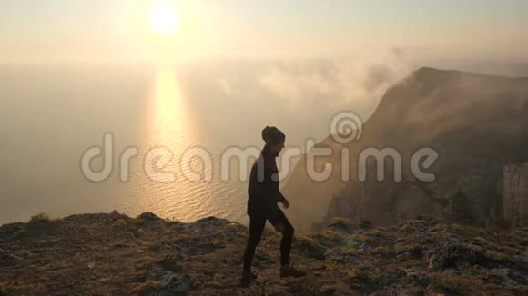 一个年轻的旅游女孩在海边的一个高高的悬崖峭壁上与一个带着绷带的女孩走在一起的特写镜头视频的预览图