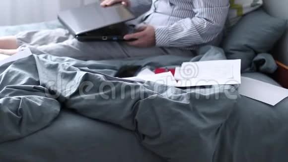 有笔记本电脑的成年女性坐在家里办公室的床上支付账单视频的预览图