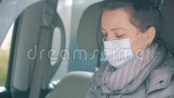女在车上脸上戴着外科口罩消毒手COVID19冠状病毒视频的预览图