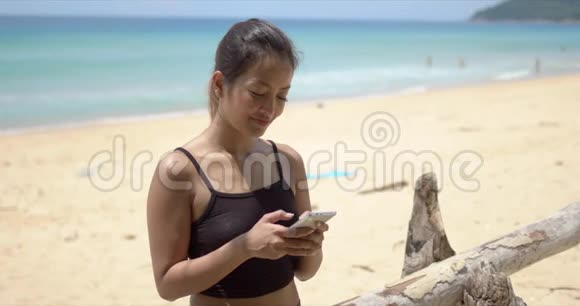 在海滩上使用智能手机的少数民族运动员视频的预览图