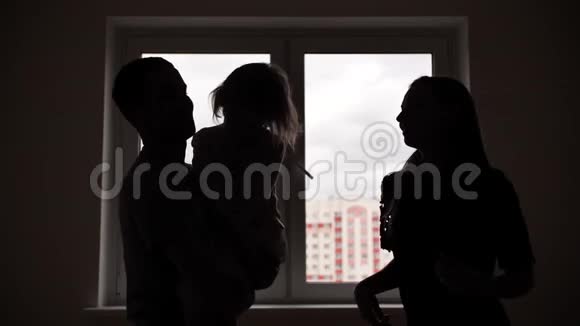 一个跳舞的年轻家庭的剪影他的公寓里有一个窗户背景下的孩子视频的预览图