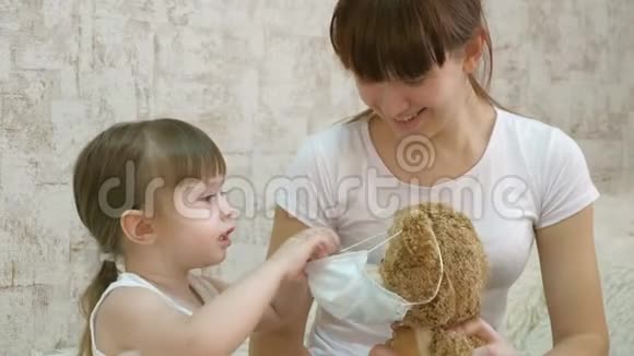 小女孩检疫在玩具熊上戴上医疗面具预防冠状病毒和流感婴儿游戏视频的预览图