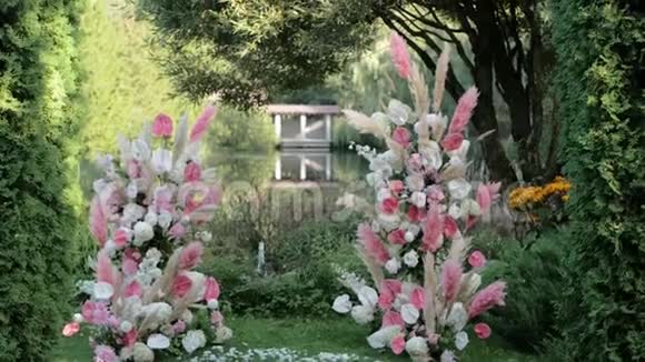美丽的拱门由粉红色和黄色的草和玫瑰在婚礼上制成视频的预览图