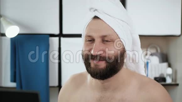 人佩服自己在浴室里一个穿着毛巾的可爱的人在镜子里看着他的美丽视频的预览图