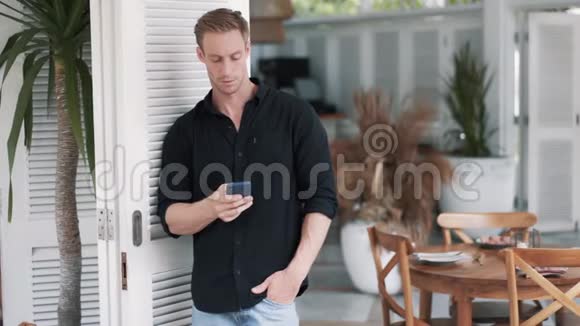 穿衬衫的帅哥站在时尚的咖啡馆里用电话发信息视频的预览图