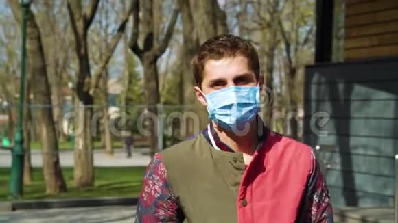 戴着医疗面具的年轻人在阳光明媚的公园散步视频的预览图